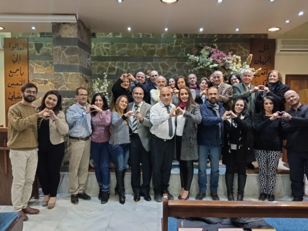Group of people stand together on a stage as they attend a marriage enrichment seminar through the Endure International ministry
