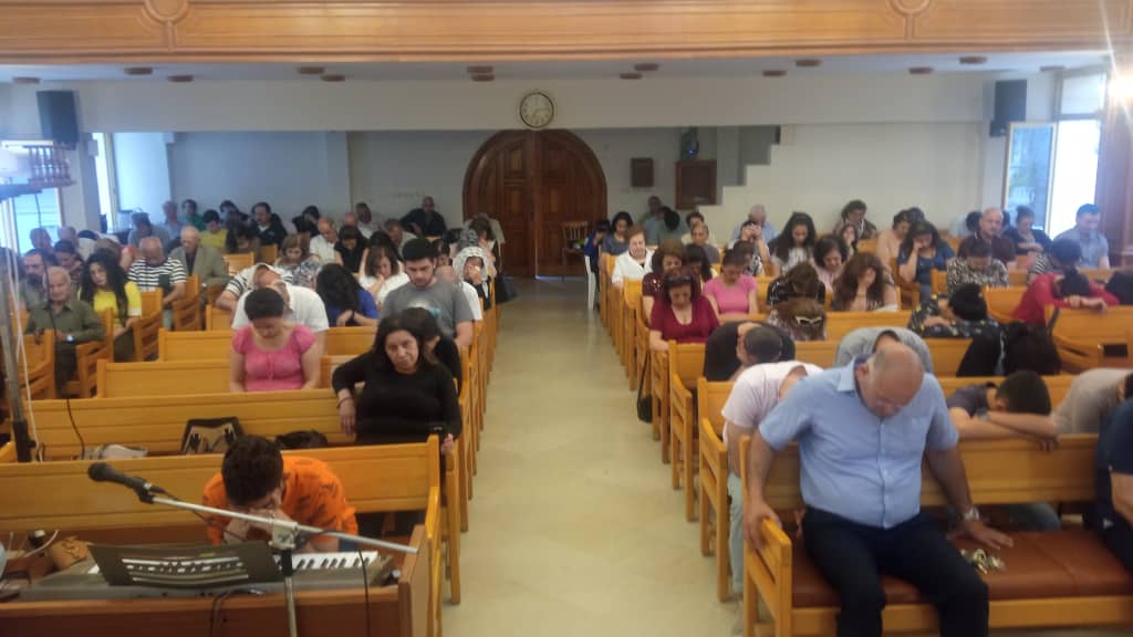 Congregants sit in wooden pews in a Church in Lattakia