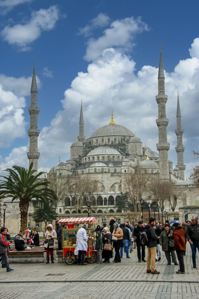 People walk and shop at food vendors in front of a large mosque in Turkey