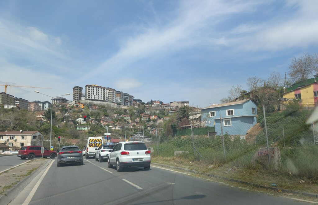 Cars sit in traffic facing a Central Asian town built into the hillside