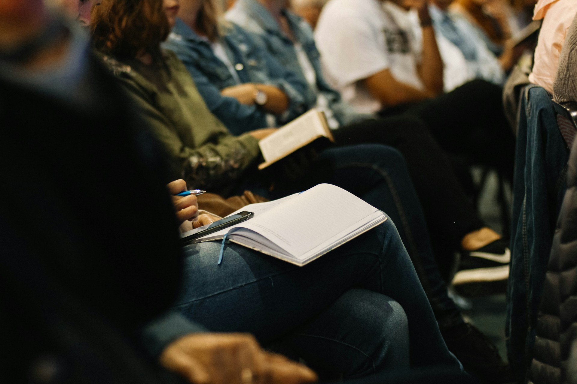 A row of people sit next to each other with Bibles open on their laps